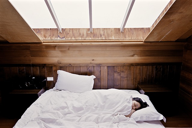 Woman asleep in white bed in wood panelled room